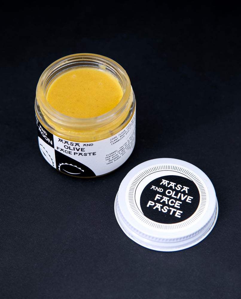 open glass jar of Fat and the Moon's "Masa and Olive Face Paste", revealing a golden yellow facial scrub product.