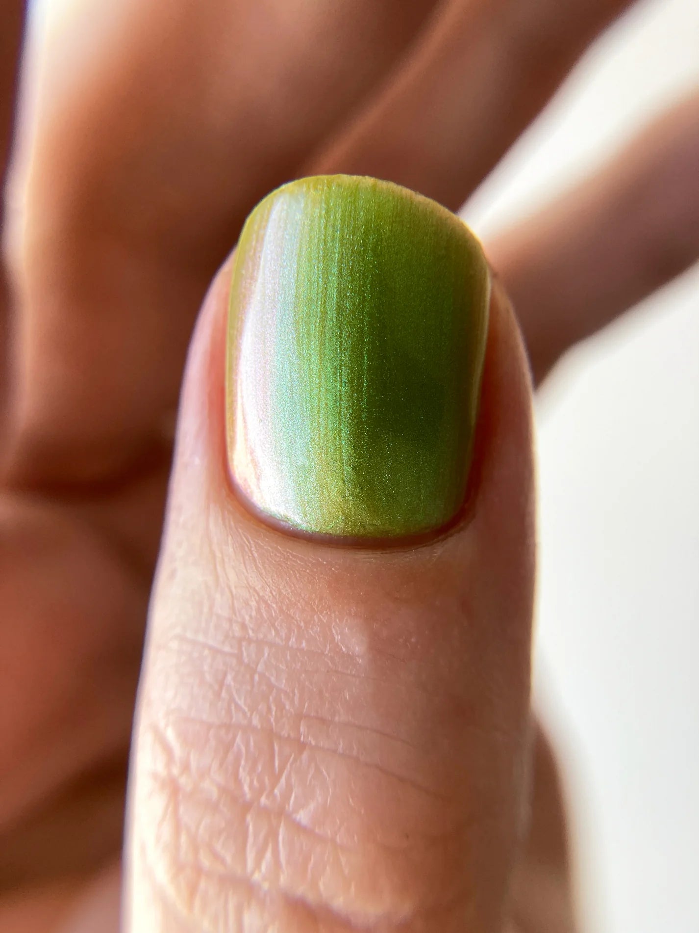Close-up of a finger with green nail polish on a blurred background