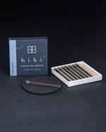 open box of HIBI incense matches, individual matches are nestled in a corrugated cardboard insert, a match is sitting on a small heatproof  burn mat