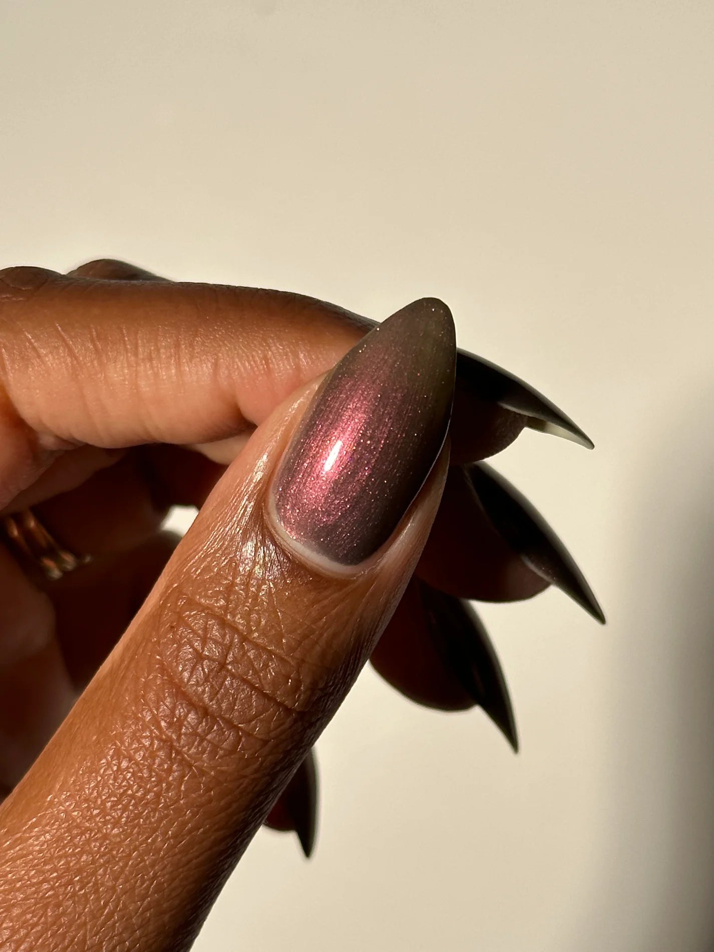 Close-up of a hand with a metallic pink copperish nail polish