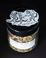 Open jar of blueberryams' "Alight in the Dark" herbal tea. Whole cardamom pods and other botanical ingredients are visible.