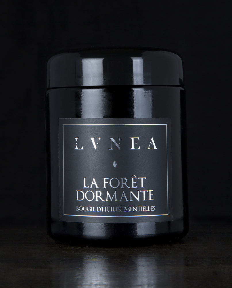 LVNEA’s La Foret Dormante candle housed in a resealable 8 ounce black glass jar on a black background
