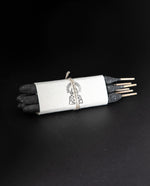 one bundle of Incausa's hand-rolled pure breu incense wrapped in white paper and twine, on a black background
