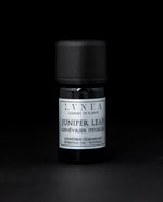 5ml black glass bottle of LVNEA's juniper leaf essential oil on black background. The label on the bottle is silver.