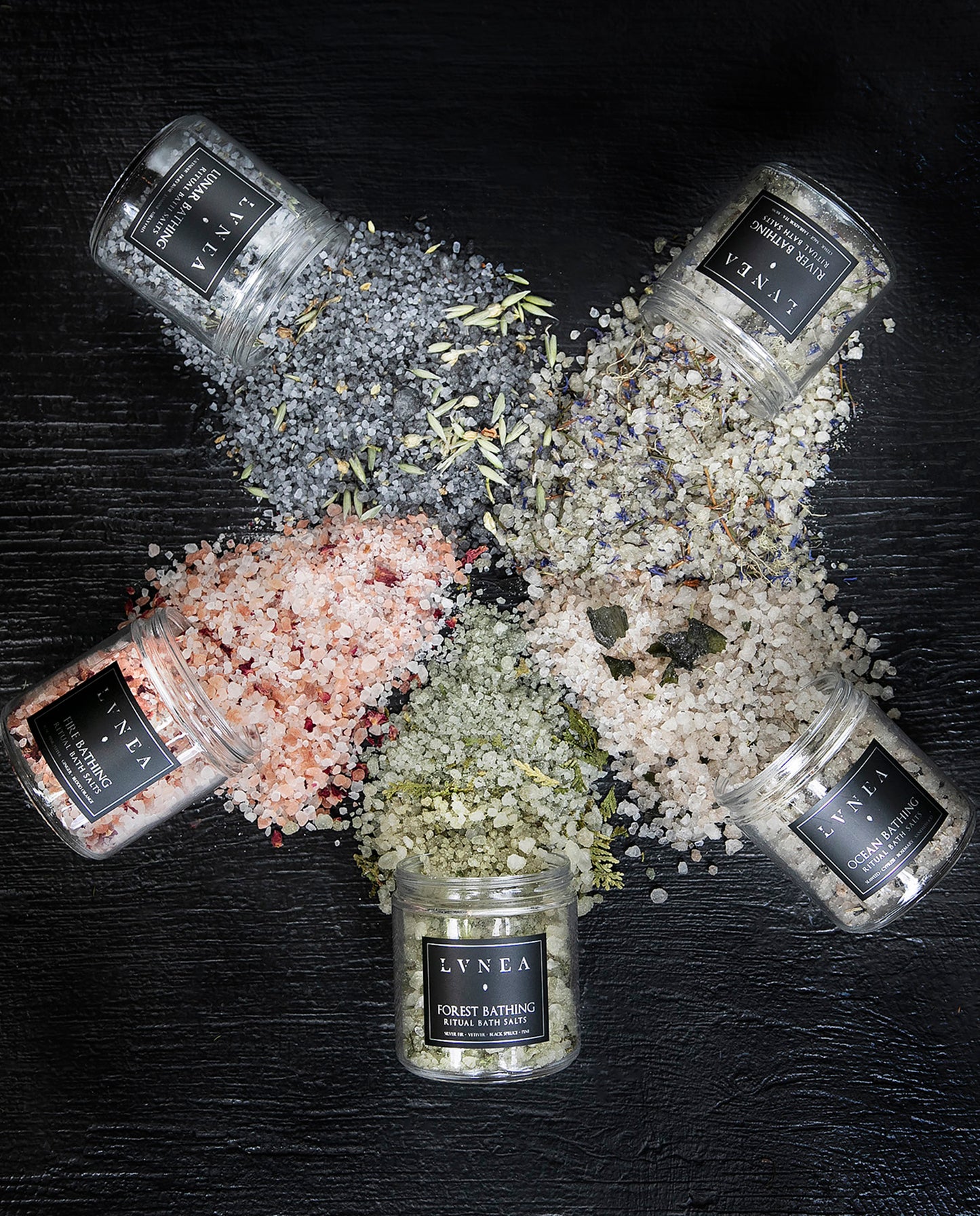 All five of LVNEA's elemental ritual bath salts arranged in a circle and spilling over with colourful salt blends.