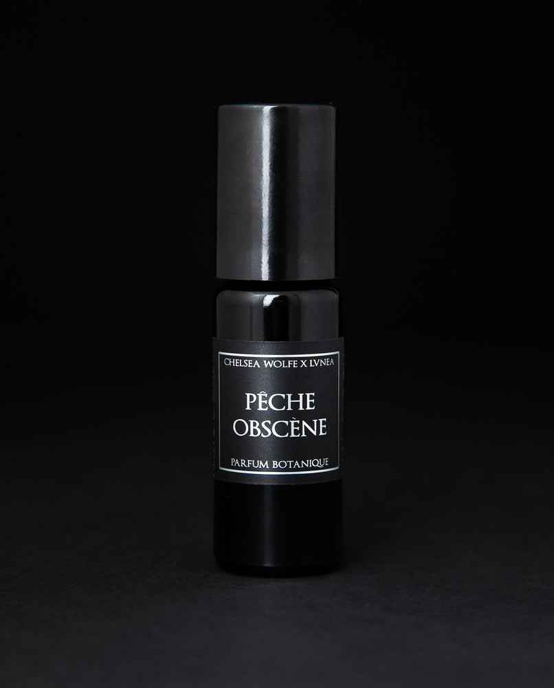 10ml black glass bottle of LVNEA's Pêche Obscène natural roll on perfume on black background
