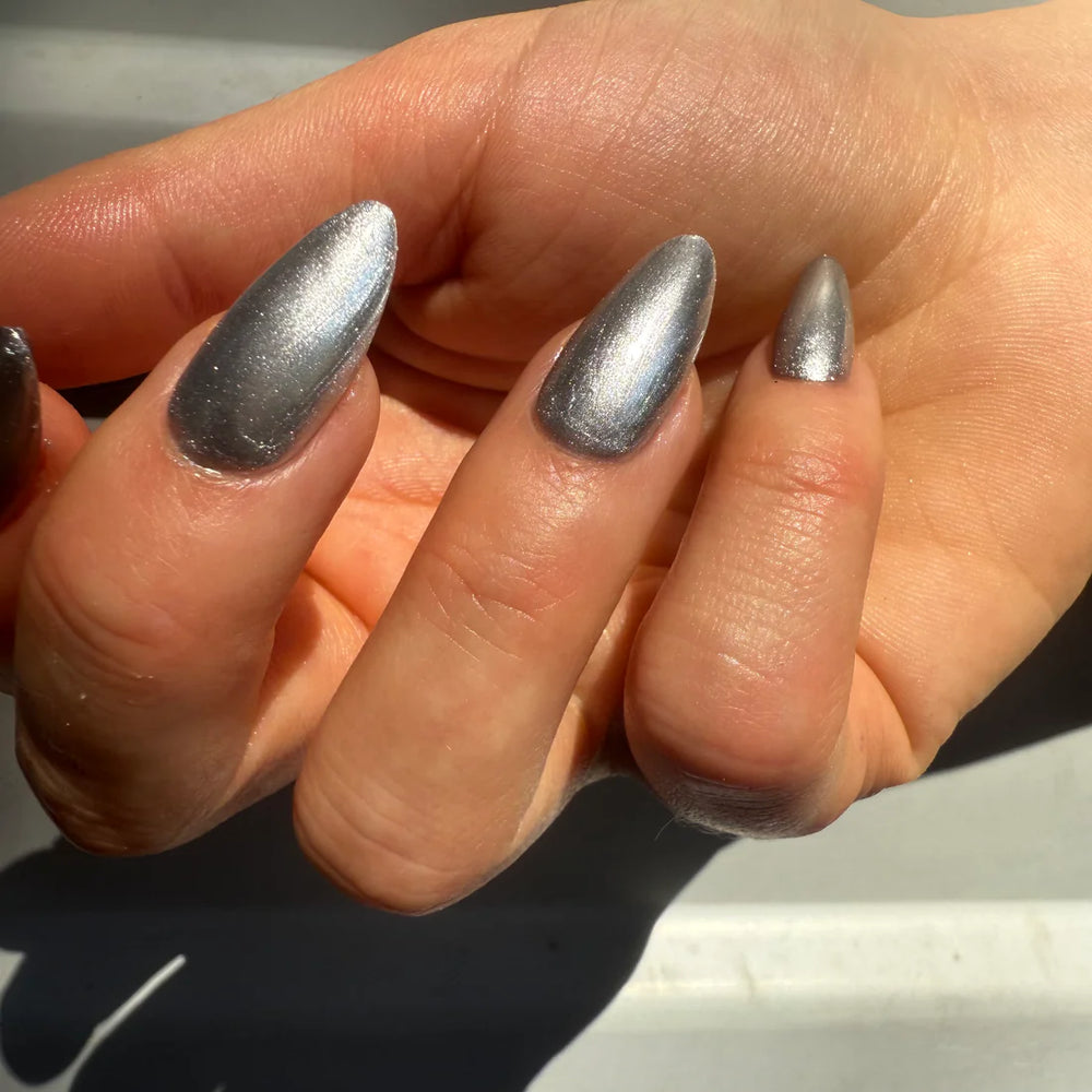 
                      
                        Close-up of a hand with silver nail polish on a neutral background
                      
                    