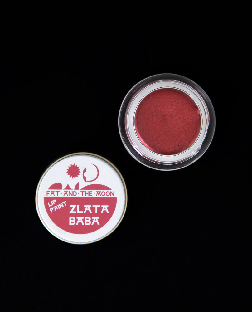 Open jar of Fat and the Moon's "Zlata Baba" lip paint. The glass jar is open, revealing a shimmering true red lip paint.