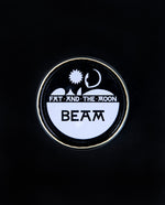 closed glass pot of Fat and the Moon's "Beam" highlighter seen from above on black background