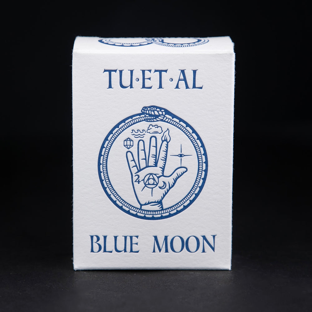 White cardboard soap box containing TU-ET-AL's "Blue Moon" soap. There is an illustration of a snake eating it's own tail, and an alchemical hand on front in blue.
