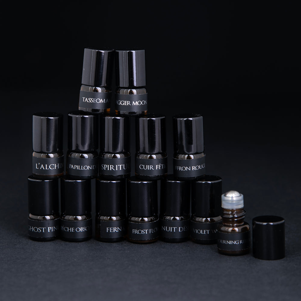 All 14 parfum botanique sample bottles stacked in a pyramid. One bottle is open, revealing the roller ball top.