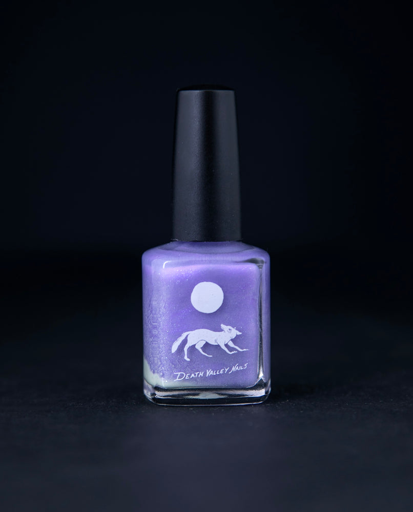 "Gris-Gris of the Bog" nail polish by Death Valley Nails on black background. The polish colour is lilac purple with silvery flecks.