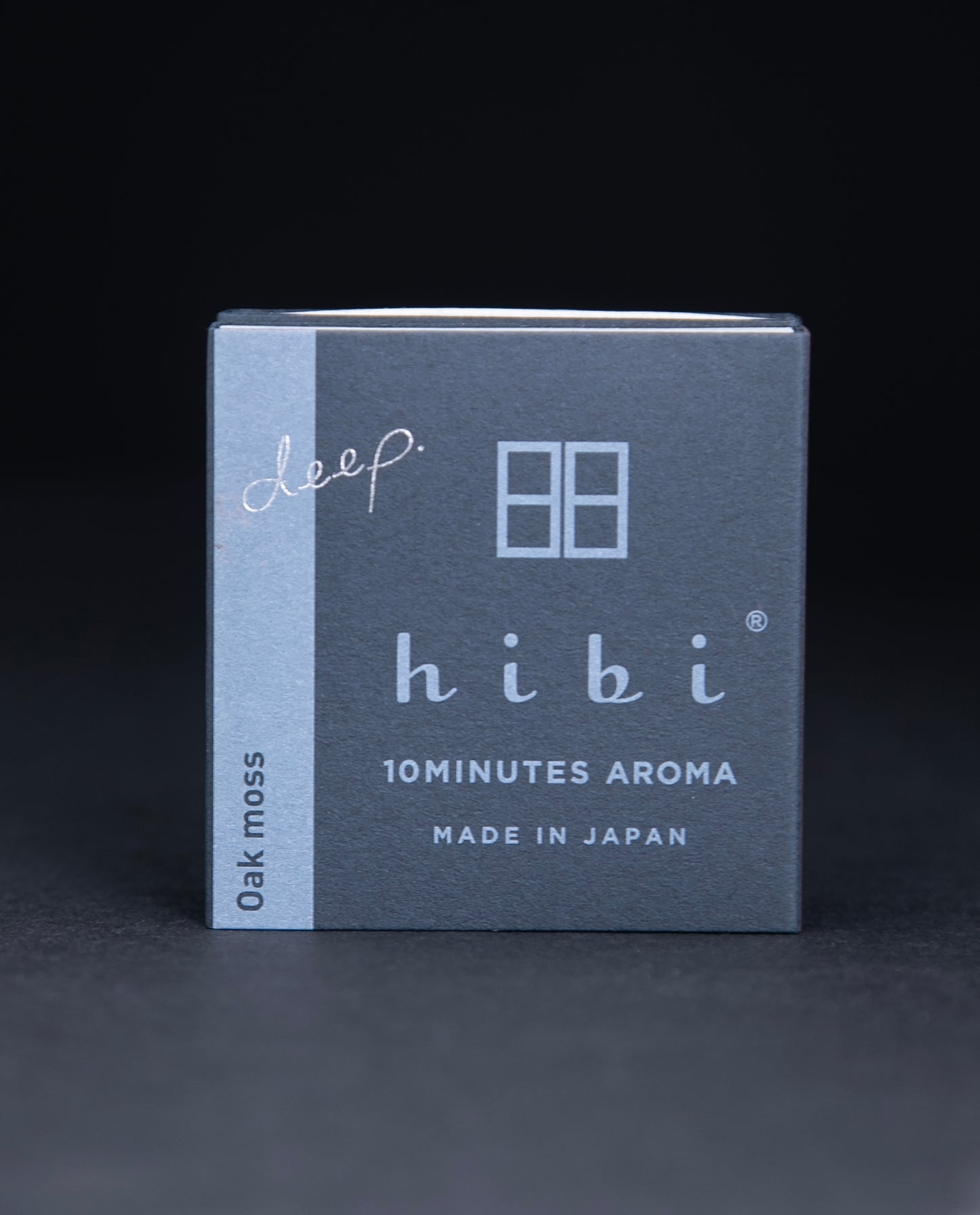 Dark slate grey paper box containing HIBI "oakmoss" incense matches, sitting on black background