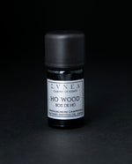 5ml black glass bottle of LVNEA's ho wood essential oil on black background. The label on the bottle is silver.