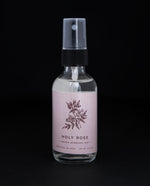 2oz clear glass bottle with black spray top of Rowan & Sage's "Holy Rose" hydrosol. The label on the bottle is light pink.