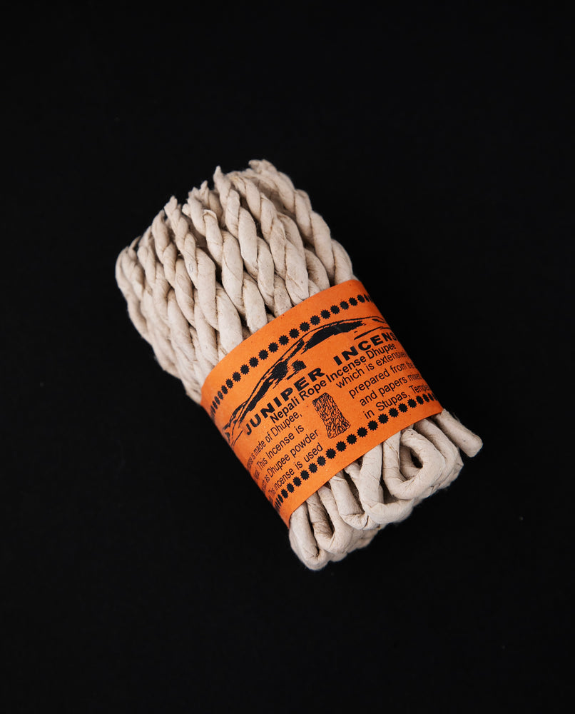 Bundle of juniper rope incense wrapped together with orange paper label.