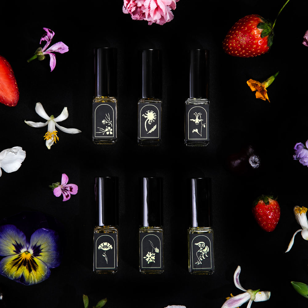 
                      
                        All 6 "Language of Flowers" vials arranged neatly in a grid, seen from overhead surrounded by colourful fresh blooms and strawberries.
                      
                    