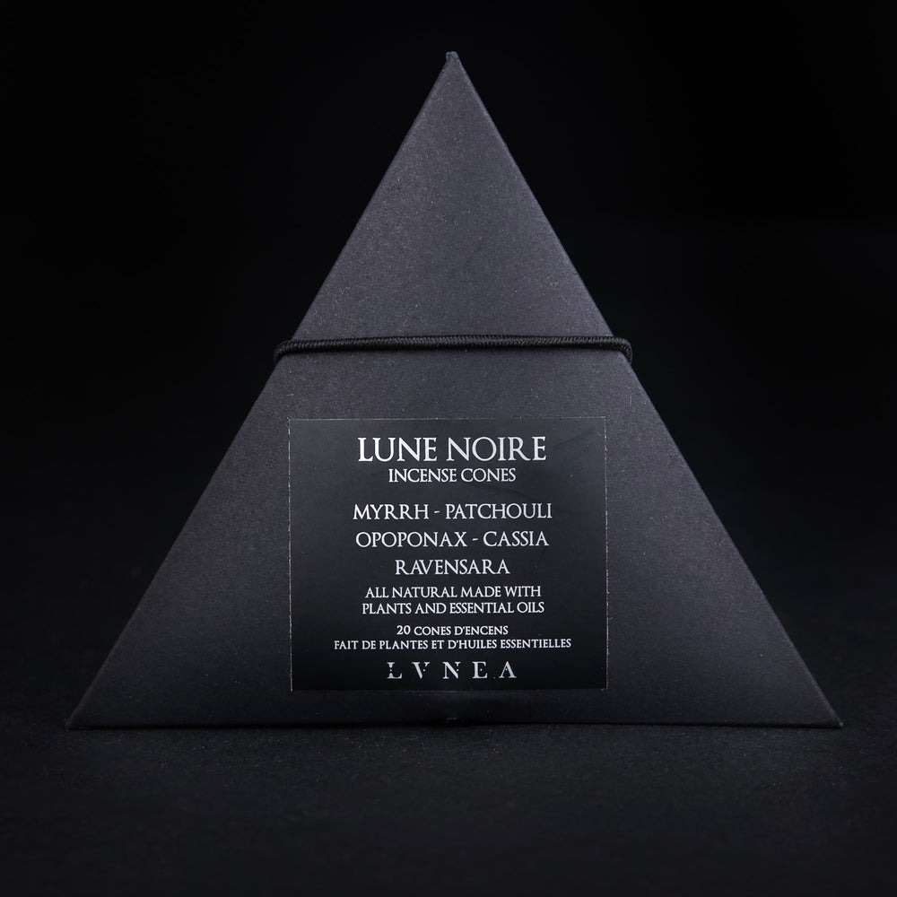 
                      
                        A closed black paper pyramid box of LVNEA's 'Lune Noire' incense. The black label on the box reads "Lune Noire Incense Cones: Myrrh, Patchouli, Opoponax, Cassia, Ravensara" in silver foil
                      
                    