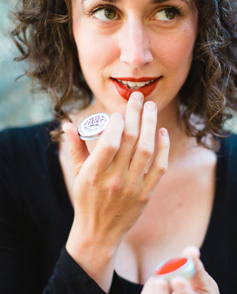 A model holds a pot of Fat and the Moon's "Mortar and Pestle" lip paint