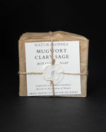 Bar of Naturasophia soap wrapped in brown paper and twine, with a label that reads "Mugwort Clary Sage". There is a white wax stamp holding the label in place.