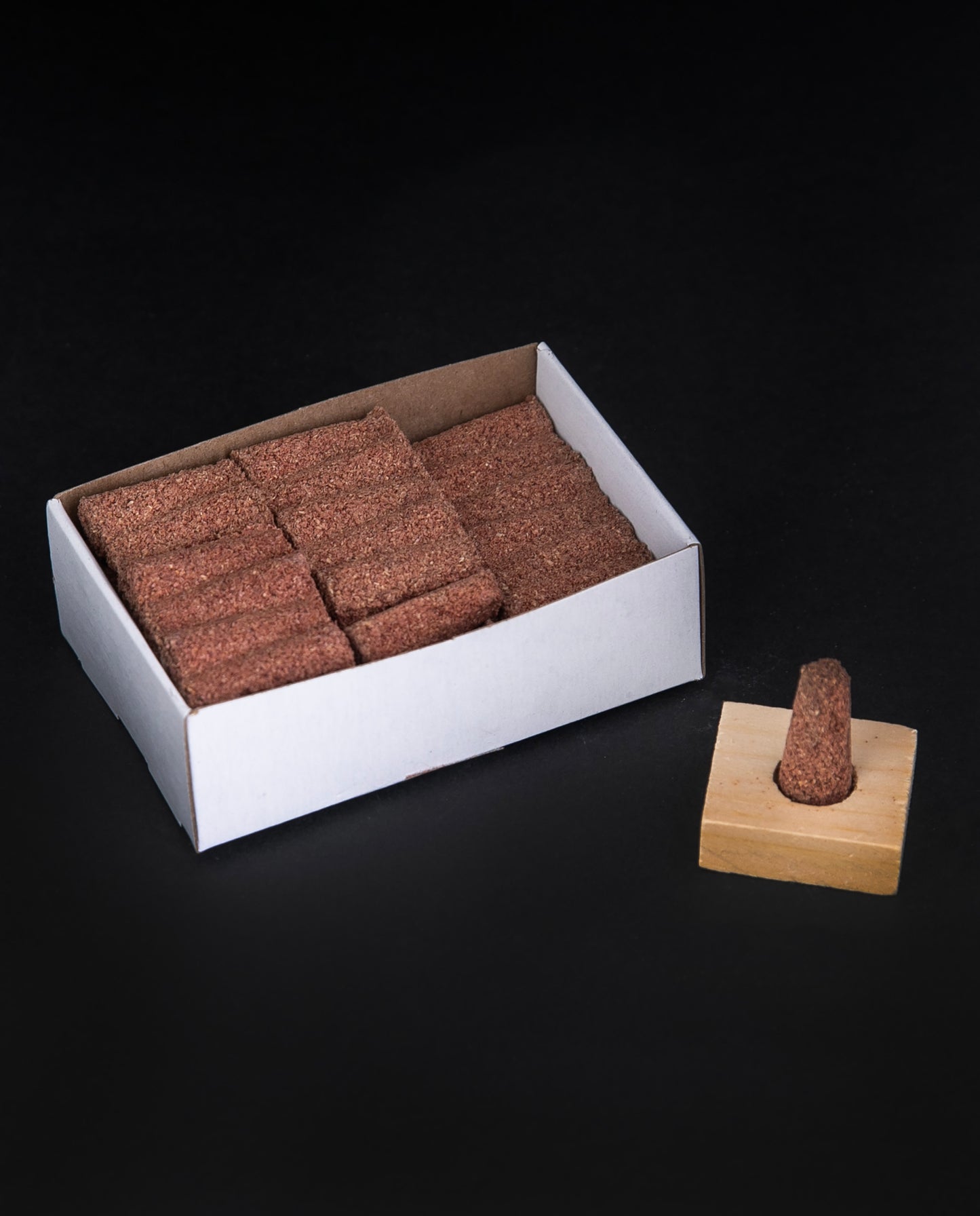 Open box of Paine's Red Cedar Incense cones sitting on black background