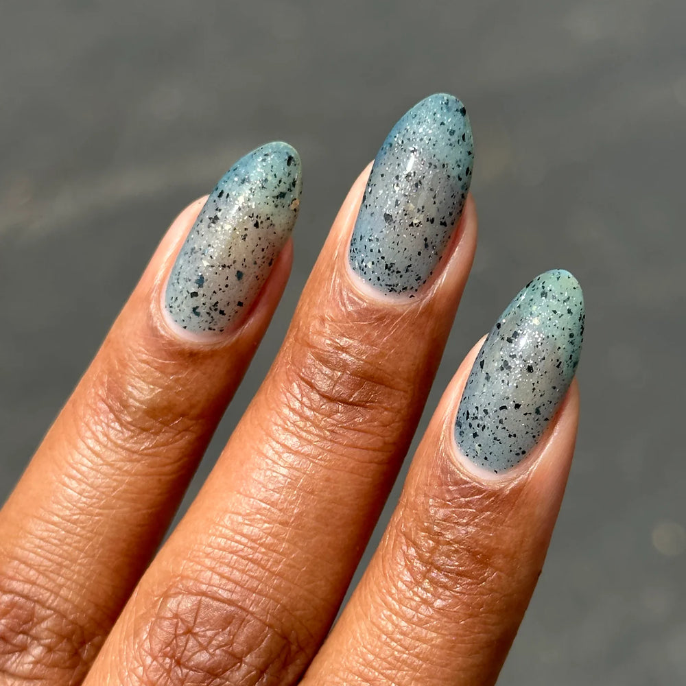 
                      
                        Close up of nails with blue speckled polish
                      
                    