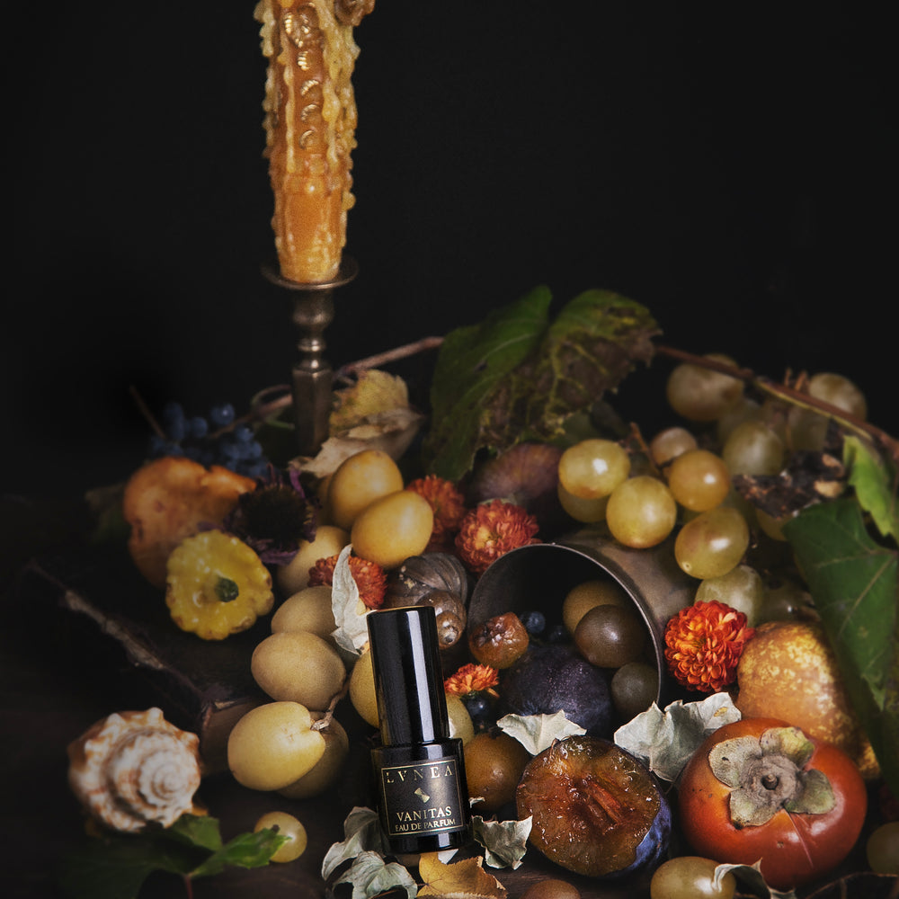 Fruit bowl with a candle and a bottle of perfume on a dark background