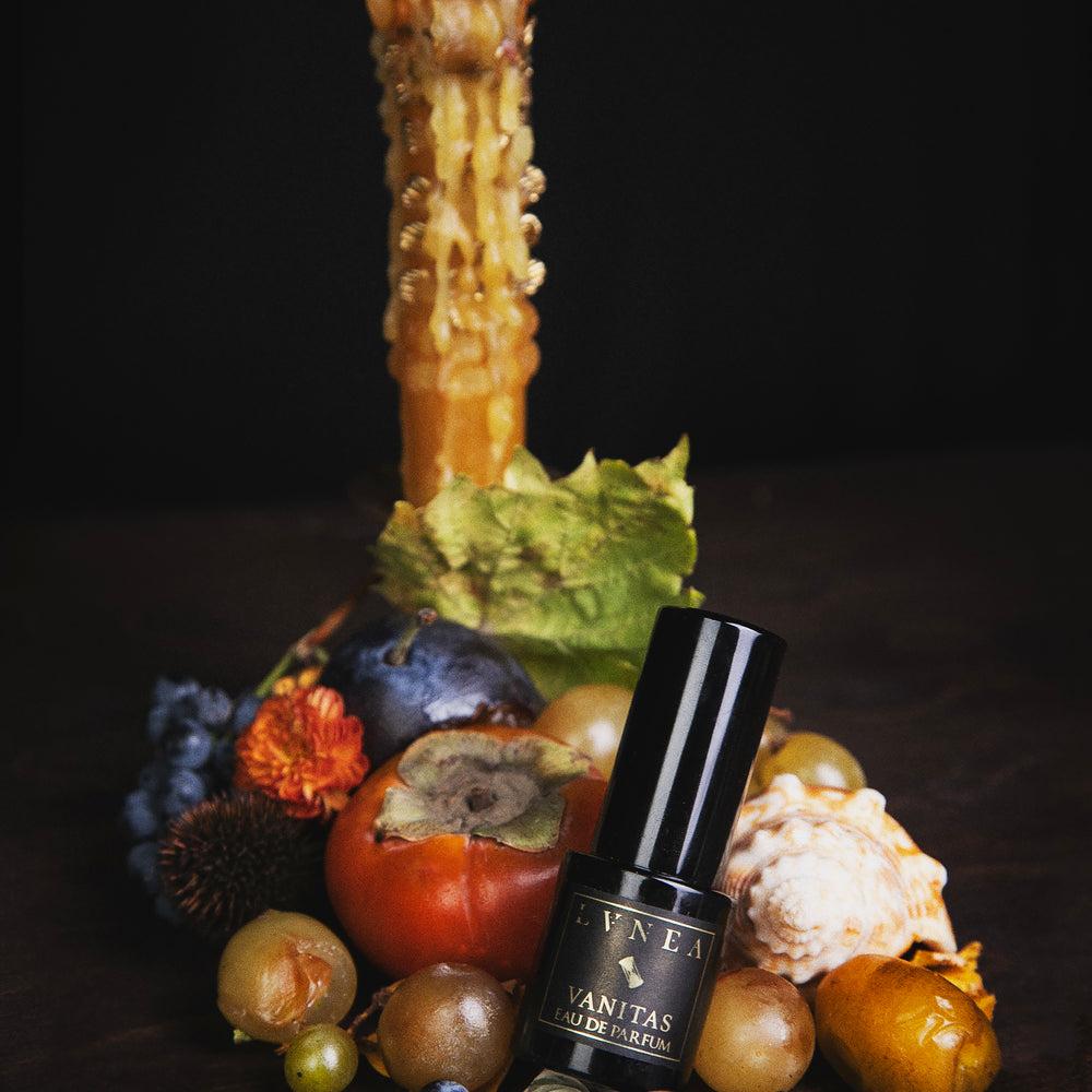 
                      
                        Vanitas limited edition black perfume bottle with decorative fruits and a candle on a dark background
                      
                    