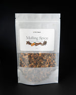 Resealable white pouch of Lit Rituals' Mulling Spice. There is a clear window in the bag, revealing the blend which features bits of cinnamon, clove, star anise, and other warming botanicals.
