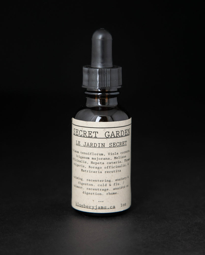 Black glass bottle with dropper top of blueberryjams' "Secret Garden" herbal tincture. 