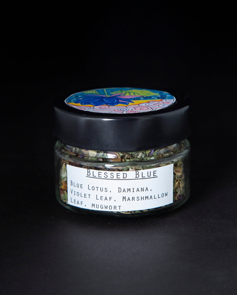 Clear glass jar with black lid containing a blue lotus herbal rolling blend. The white label reads "Blessed Blue"