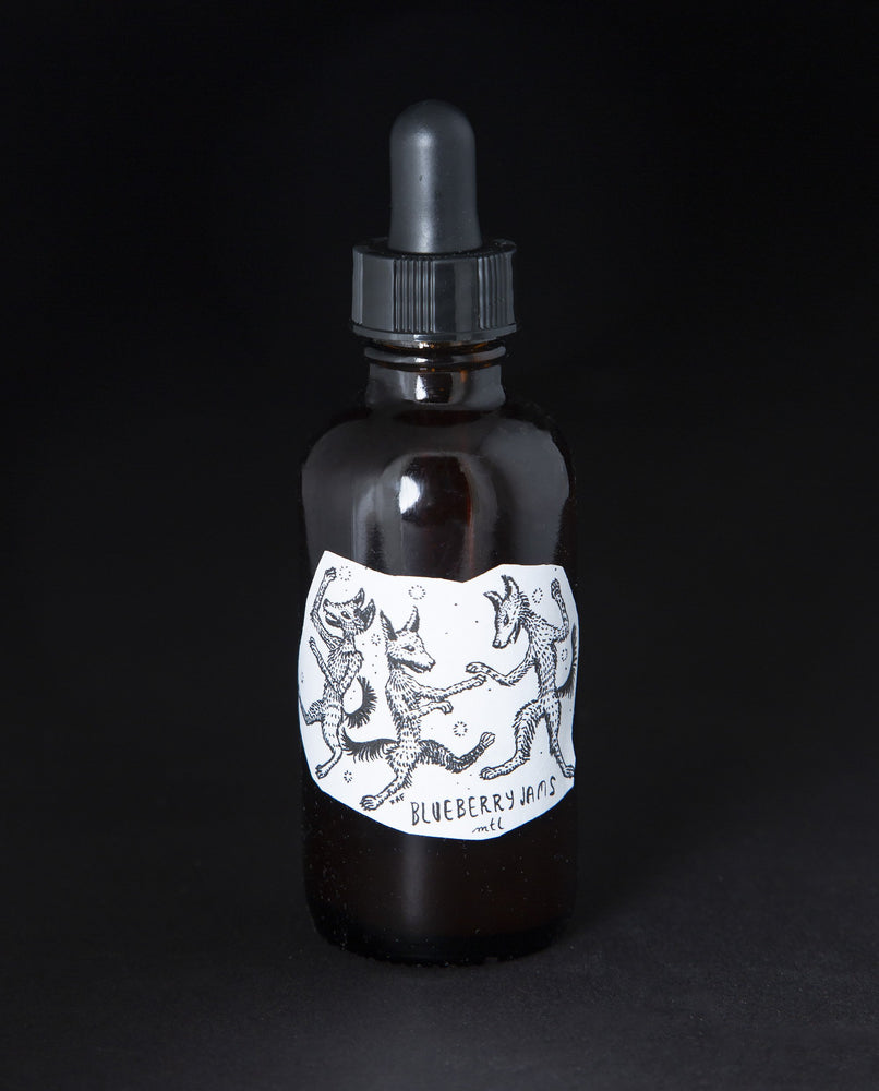 amber glass bottle with black dropper top and white label with 3 wolves dancing. The bottle contains blueberryjams' Dark of Winter Elixir