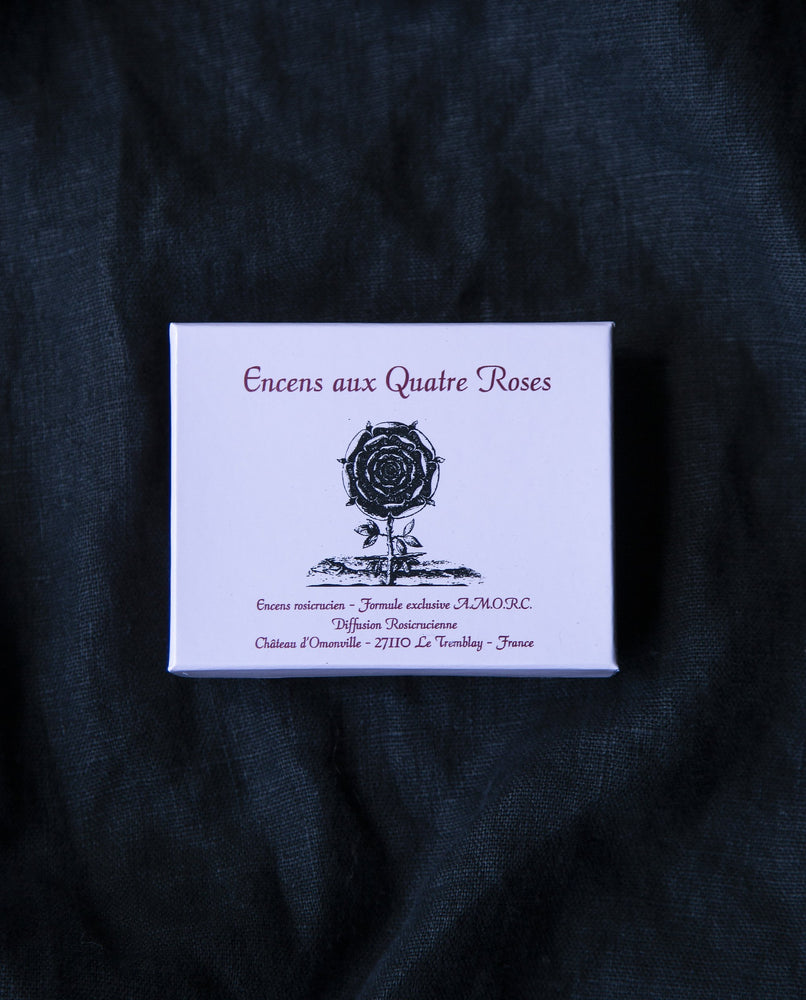 Pink box containing "Quatre Roses" Rosicrucian incense, displayed on black fabric background
