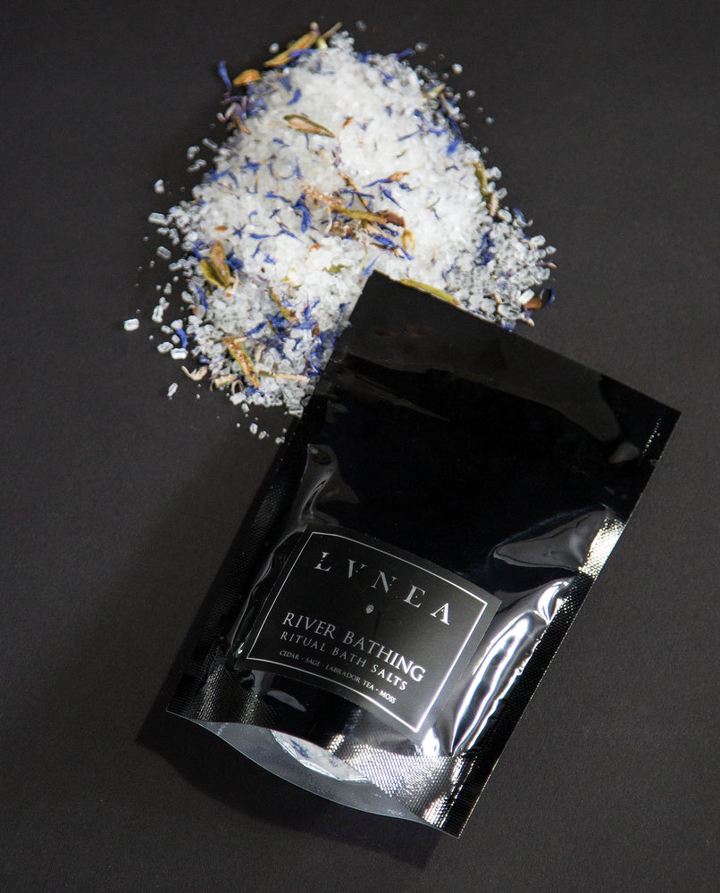 4oz black resealable pouch of LVNEA's River Bathing bath salts with a mound of salt next to it