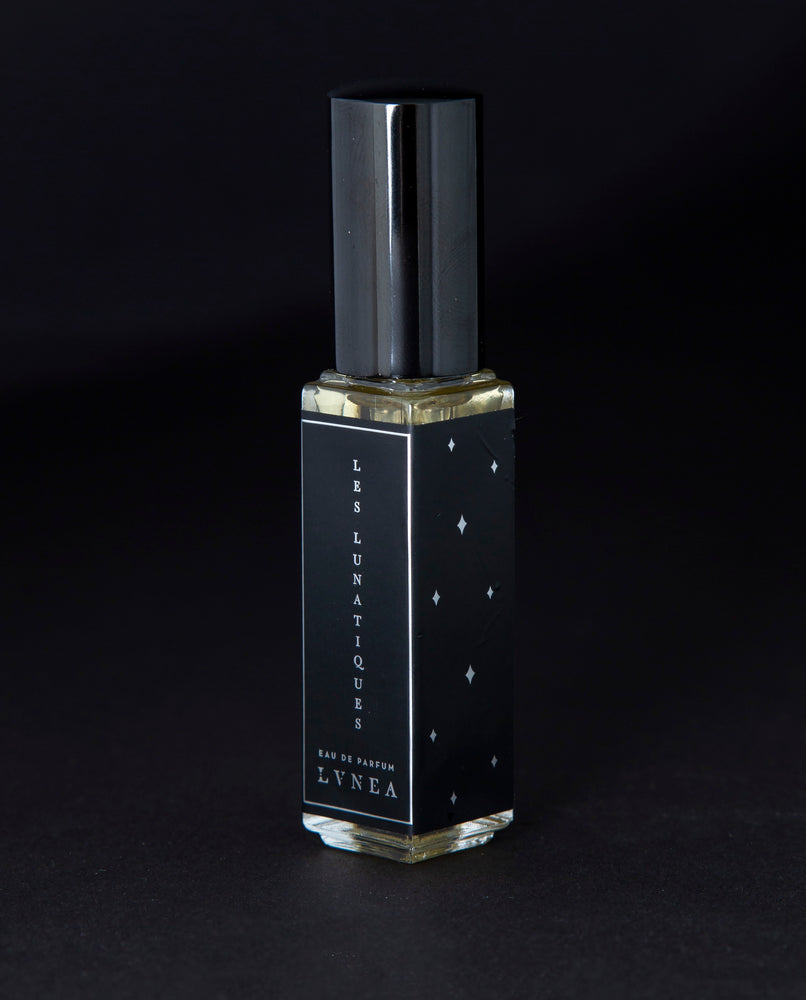 8ml clear glass bottle of LVNEA’s Les Lunatiques natural perfume on black background, bottle is rotated at a 3/4 angle exposing a star pattern on the label.