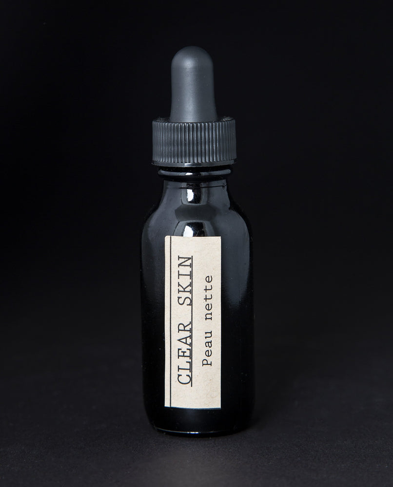 black glass bottle with black dropper top and tan label reading "Clear Skin". It contains a herbal tincture by blueberryjams