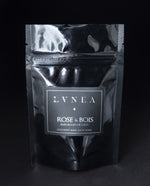 A black 2 oz resealable pouch filled LVNEA's Rose & Bois vegan coconut milk based bath soak.
