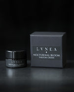 10g black glass pot of LVNEA's Nocturnal Bloom solid perfume next to its box on black background