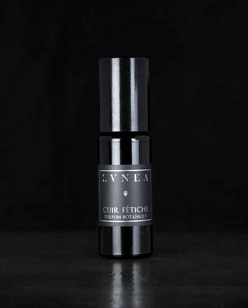 10ml black glass bottle of LVNEA's Cuir Fétiche natural roll on perfume oil on black background