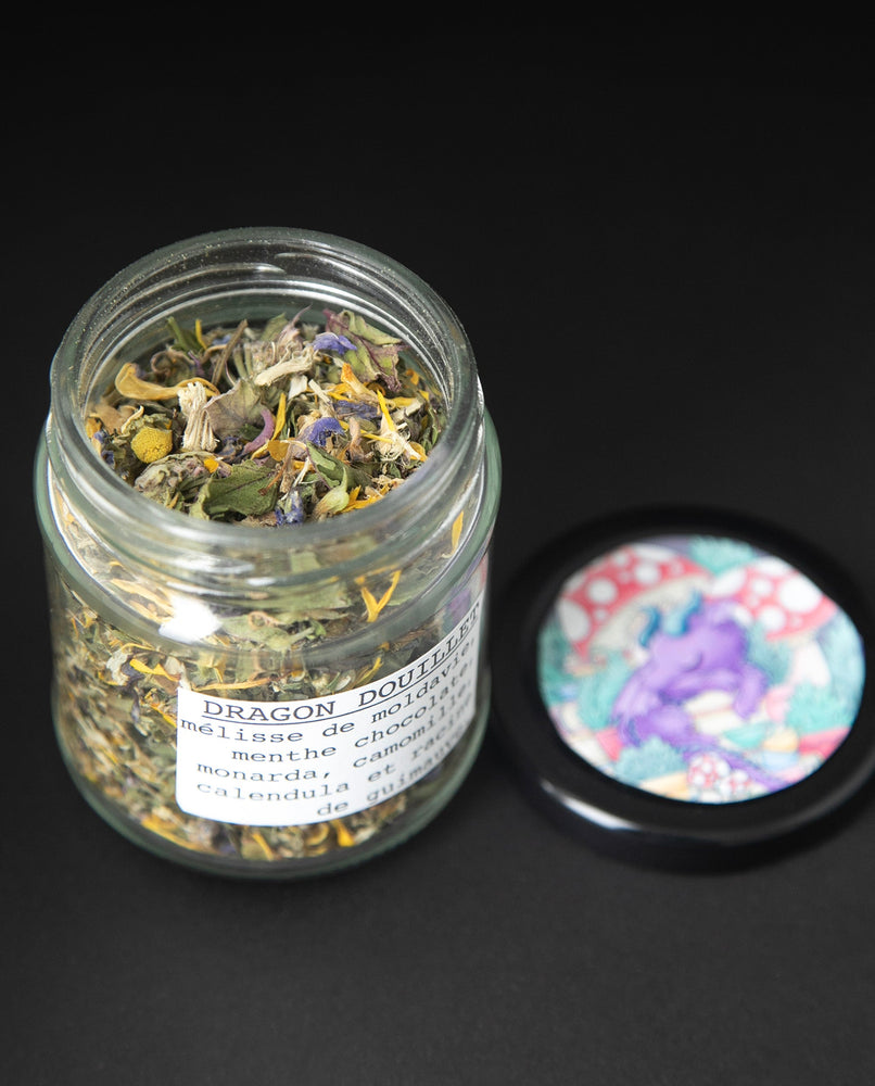 glass jar is open and seen from an elevated angle, revealing the herbal tea blend within
