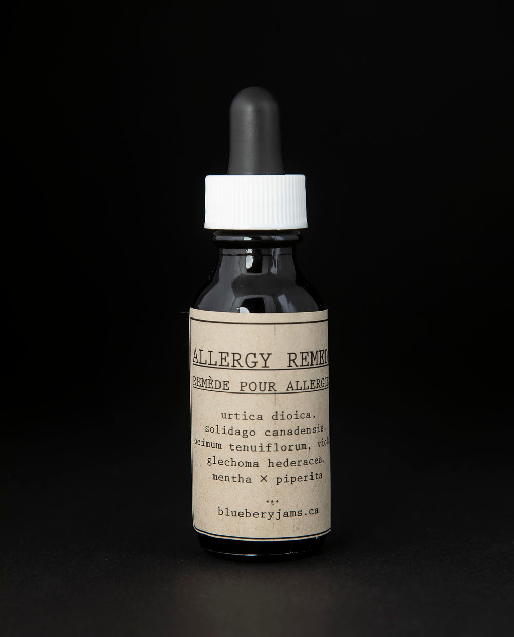 Black glass bottle with kraft paper label and dropper top. Contains blueberryjams' 