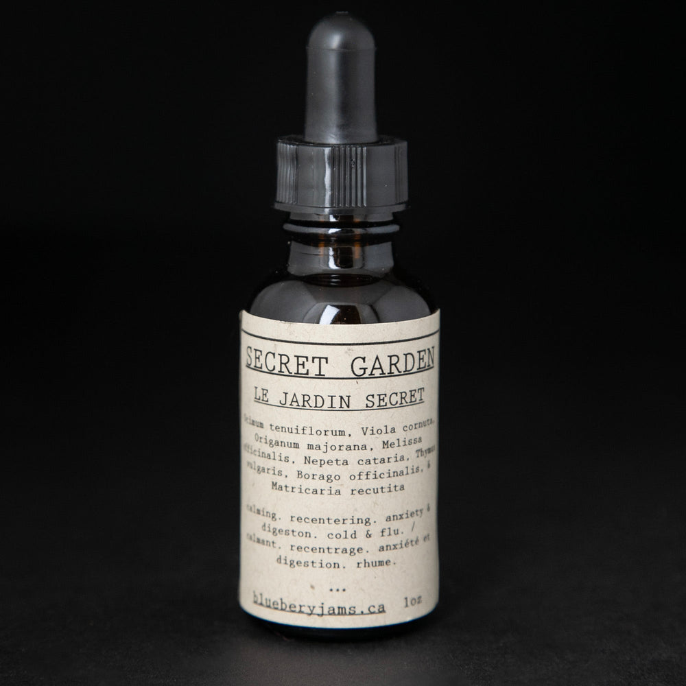 Black glass bottle with dropper top of blueberryjams' "Secret Garden" herbal tincture. 