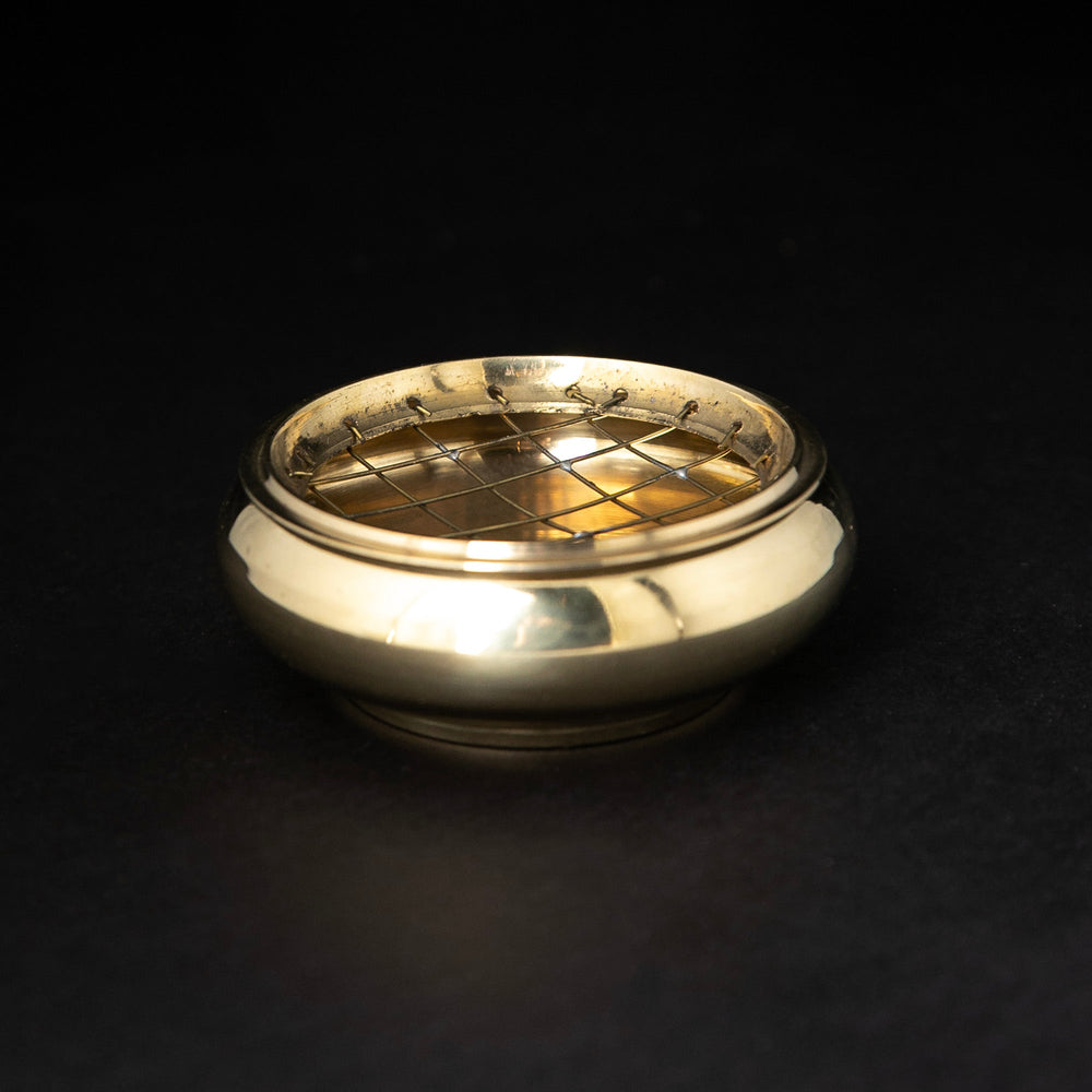 brass incense burner with brass grate on black background