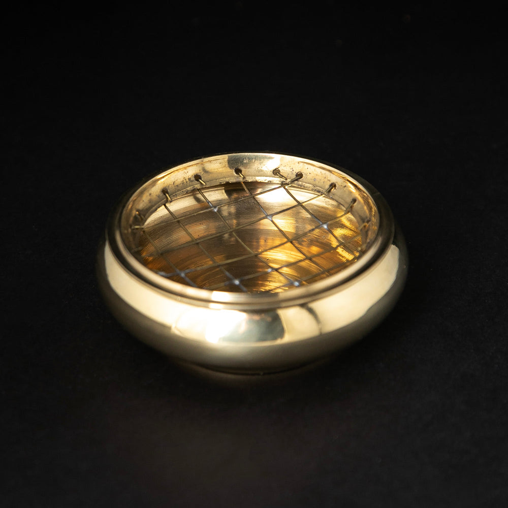 brass incense burner with brass grate on black background