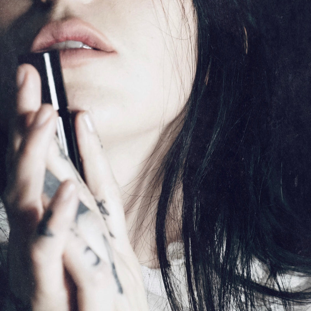 
                      
                        Singer songwriter Chelsea Wolfe cradles a bottle of her collaborative fragrance with natural and botanical perfume brand LVNEA, Pêche Obscène.
                      
                    