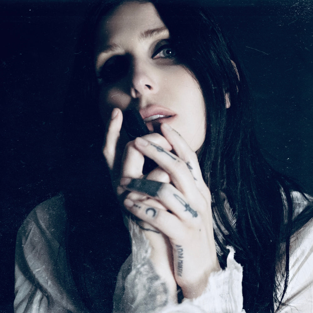 
                      
                        Singer songwriter Chelsea Wolfe cradles a bottle of her collaborative fragrance with natural and botanical perfume brand LVNEA, Pêche Obscène.
                      
                    