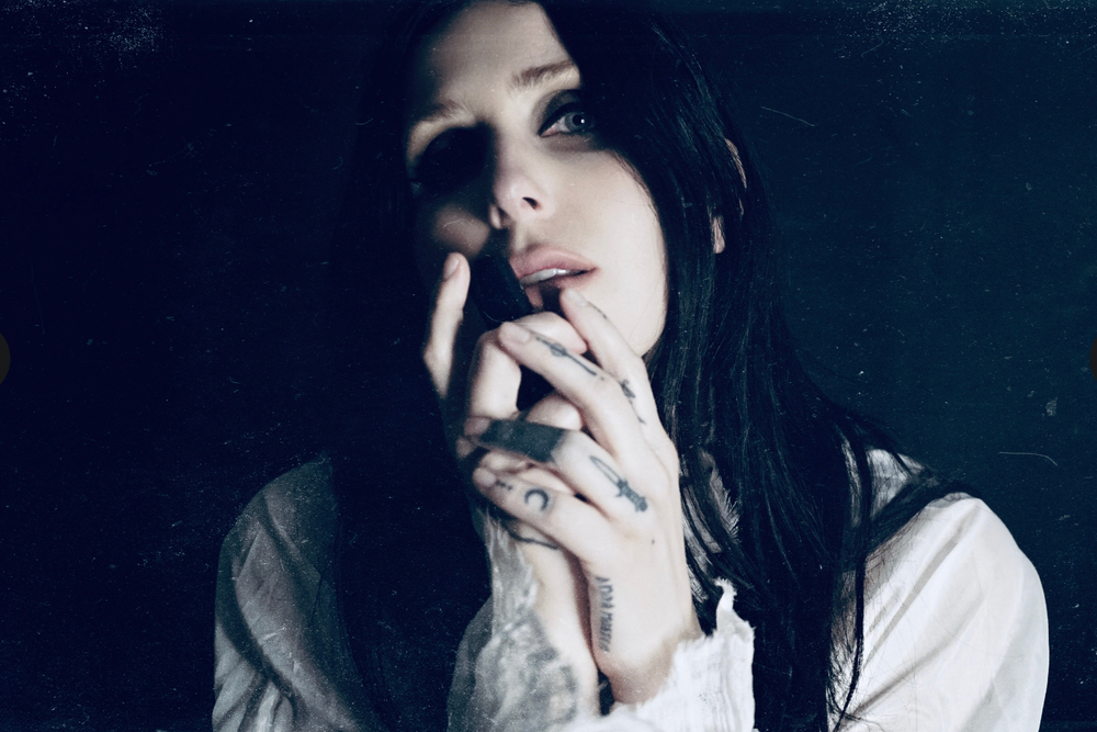 
                      
                        Singer songwriter Chelsea Wolfe cradles a bottle of her collaborative fragrance with natural and botanical perfume brand LVNEA, Pêche Obscène.
                      
                    