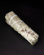 bundle of dried lemon eucalyptus wrapped in white string on black background.