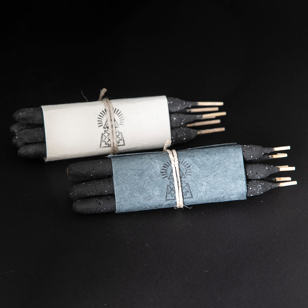 
                      
                        two bundles of Incausa's hand-rolled breu incense sticks wrapped in natural paper and twine, on a black background
                      
                    