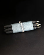 one bundle of Incausa's hand-rolled chacrona and jagube incense wrapped in white paper and twine, on a black background